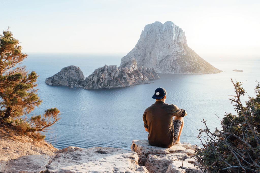 A man sitting on rocks overlooking the ocean