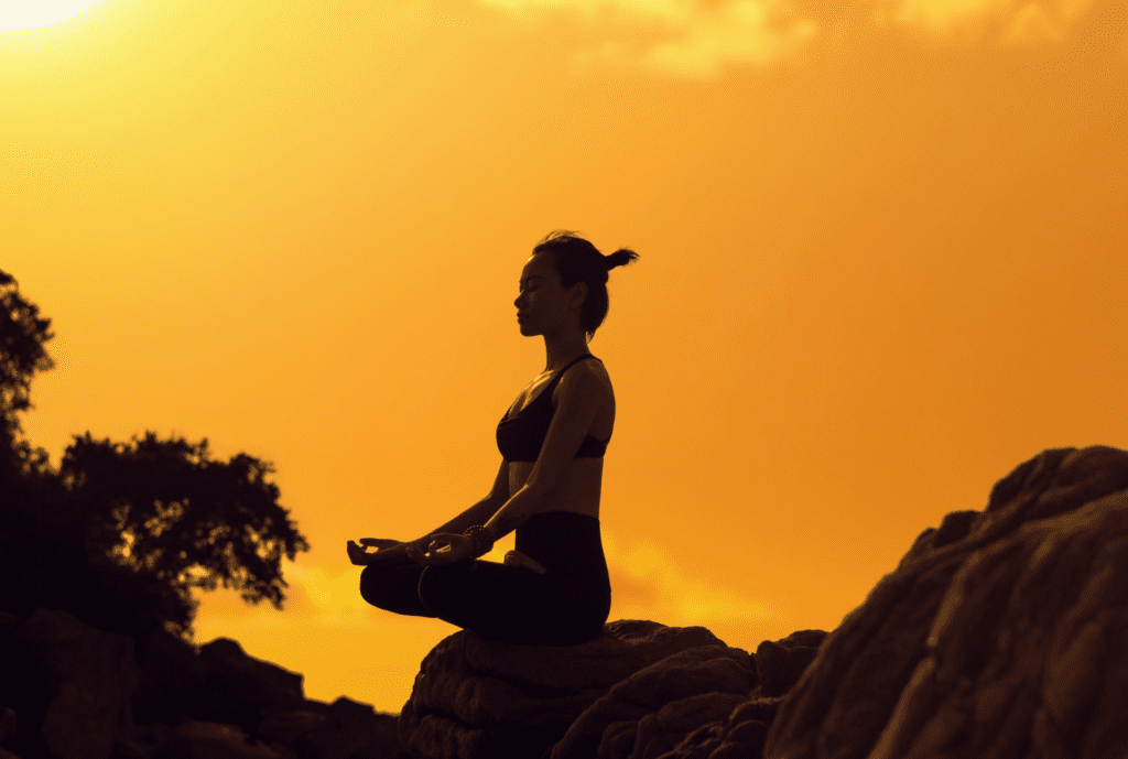 Woman meditating on a rock in the sun