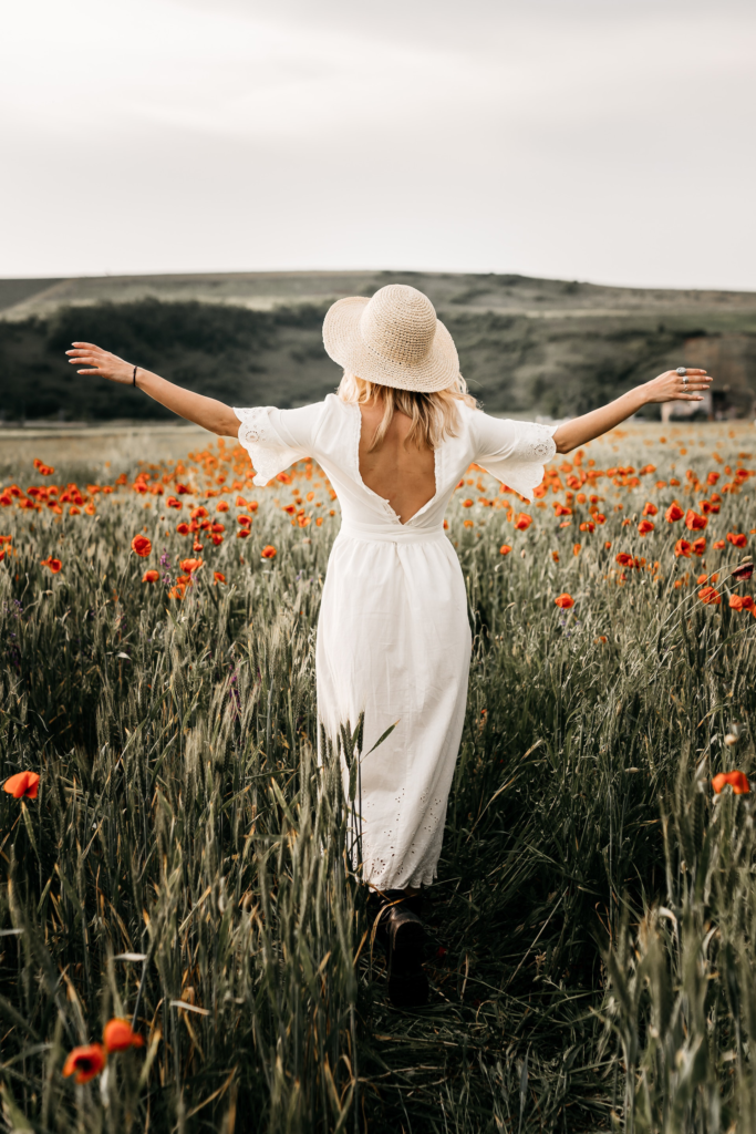 Woman walking in a field of flowers, enjoying the beautiful scenery and feeling the soft petals of the plants with her hands.
