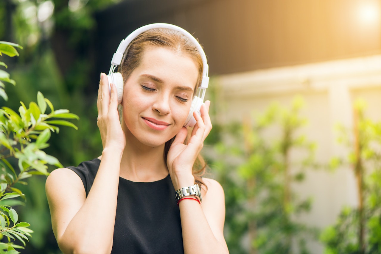 A woman wearing headphones and smiling while listening to music